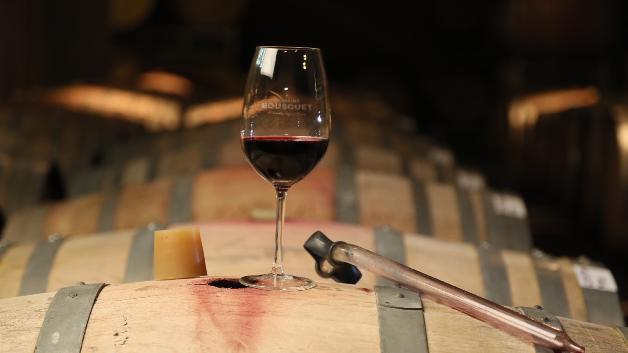 A glass of wine sits on top of a barrel and signifies increasing organic wine availability